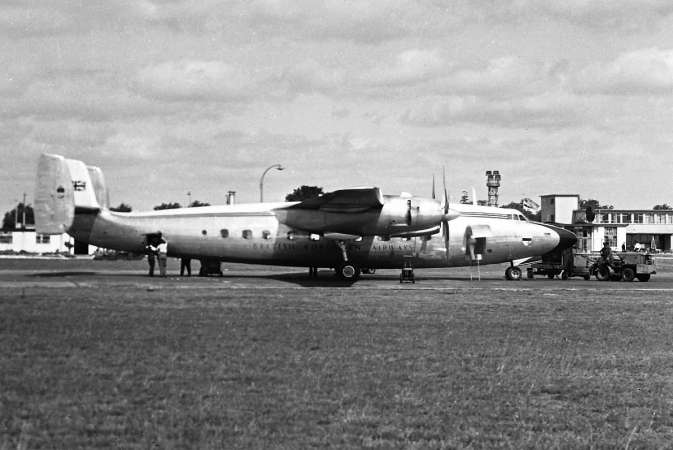 A black-and-white photograph of a twin-engined propeller airliner on an airfield